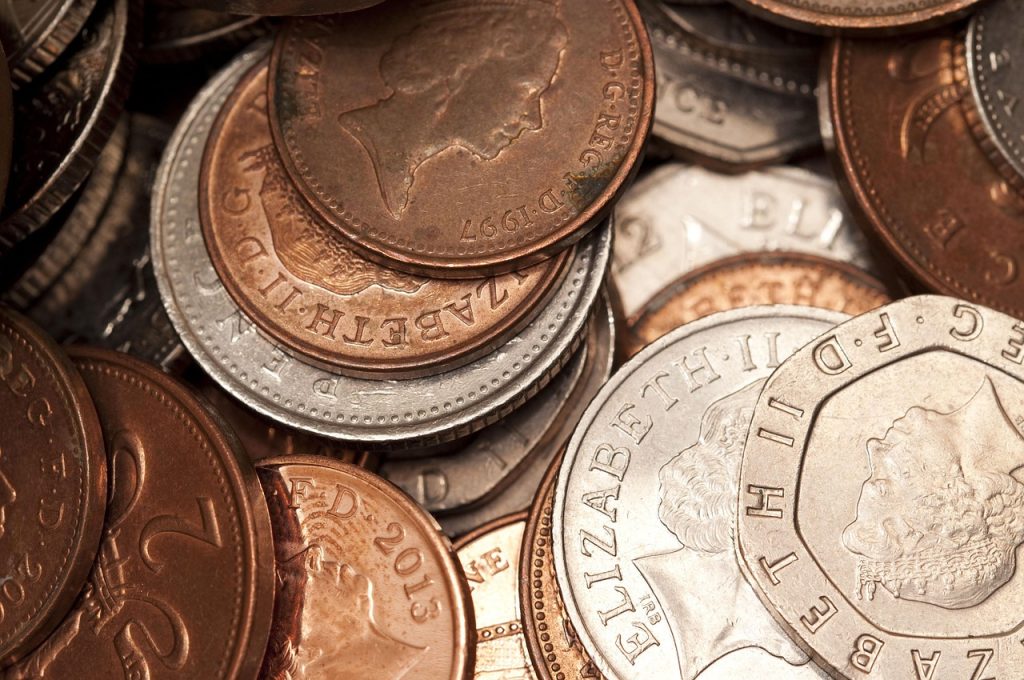 A close-up of a pile of coins labeled 'pound sterling', showcasing their distinct design and metallic sheen